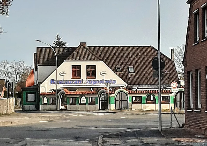 Ansicht auf die Vorderseite des Restaurants. Es ist weiß gestrichen mir grünen Fenstern.